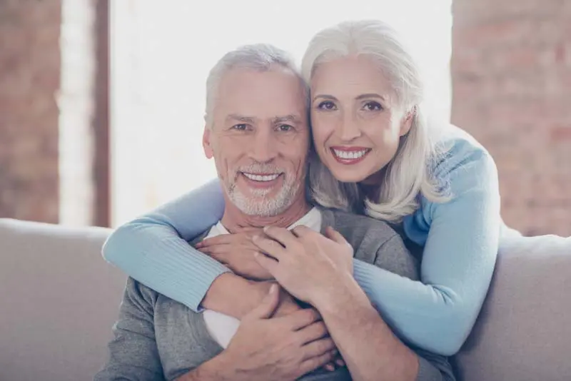 Husband and wife embracing with smiles on their faces.